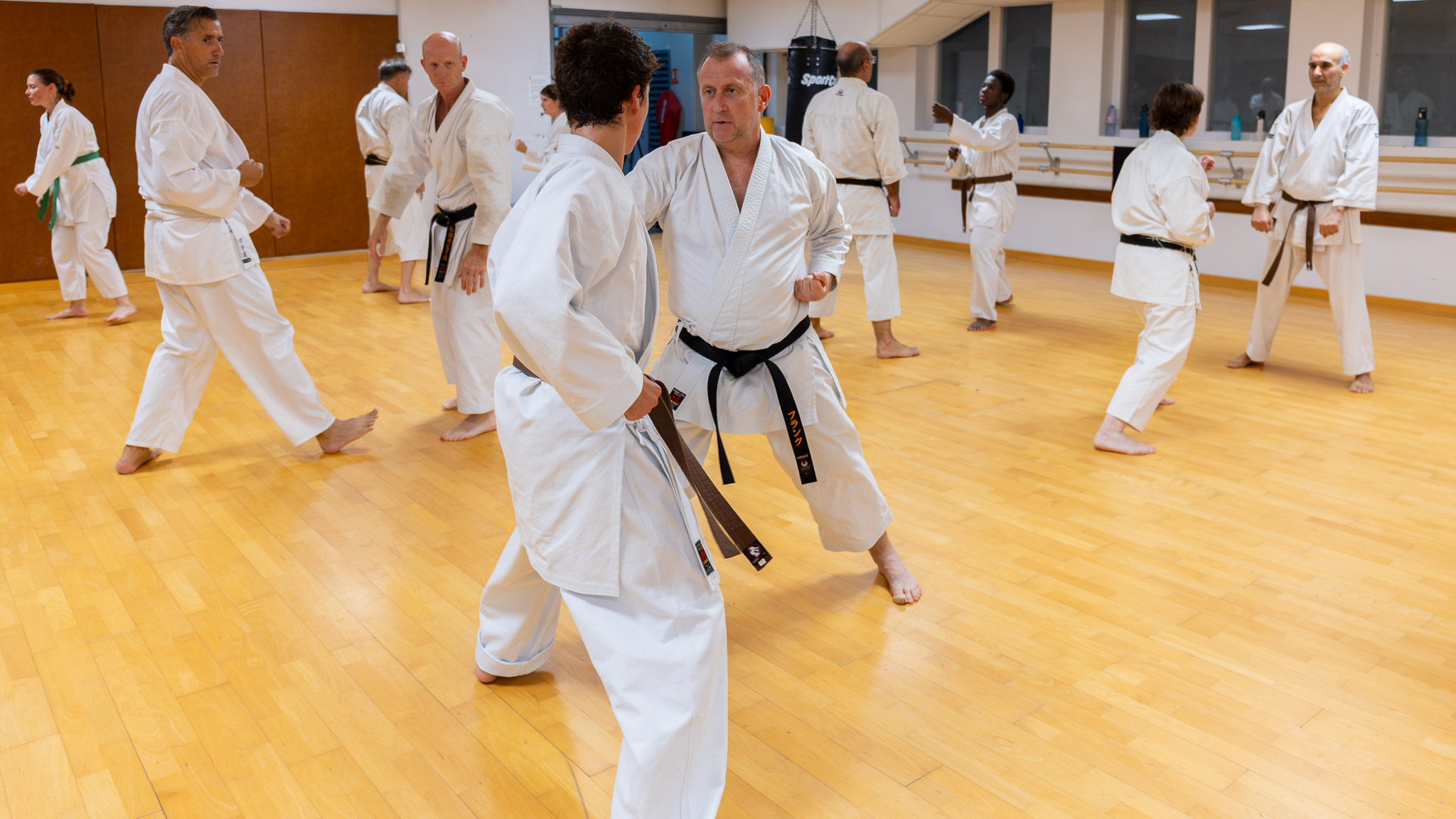 Pascal travaille le kumite avec une ceinture marron au milieu du groupe