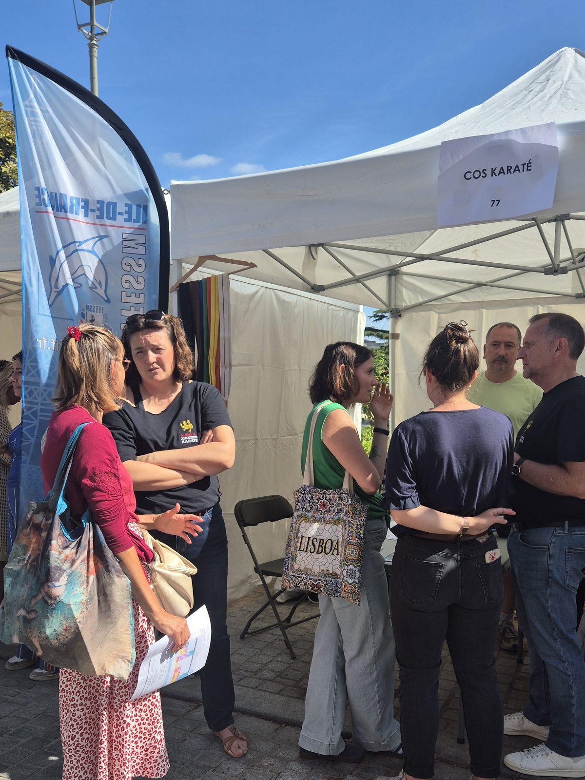 Des visiteurs discutent avec les bénévoles devant le stand